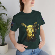 Person wearing a Black Heather t-shirt with a gold and black graphic design, standing indoors next to a plant.